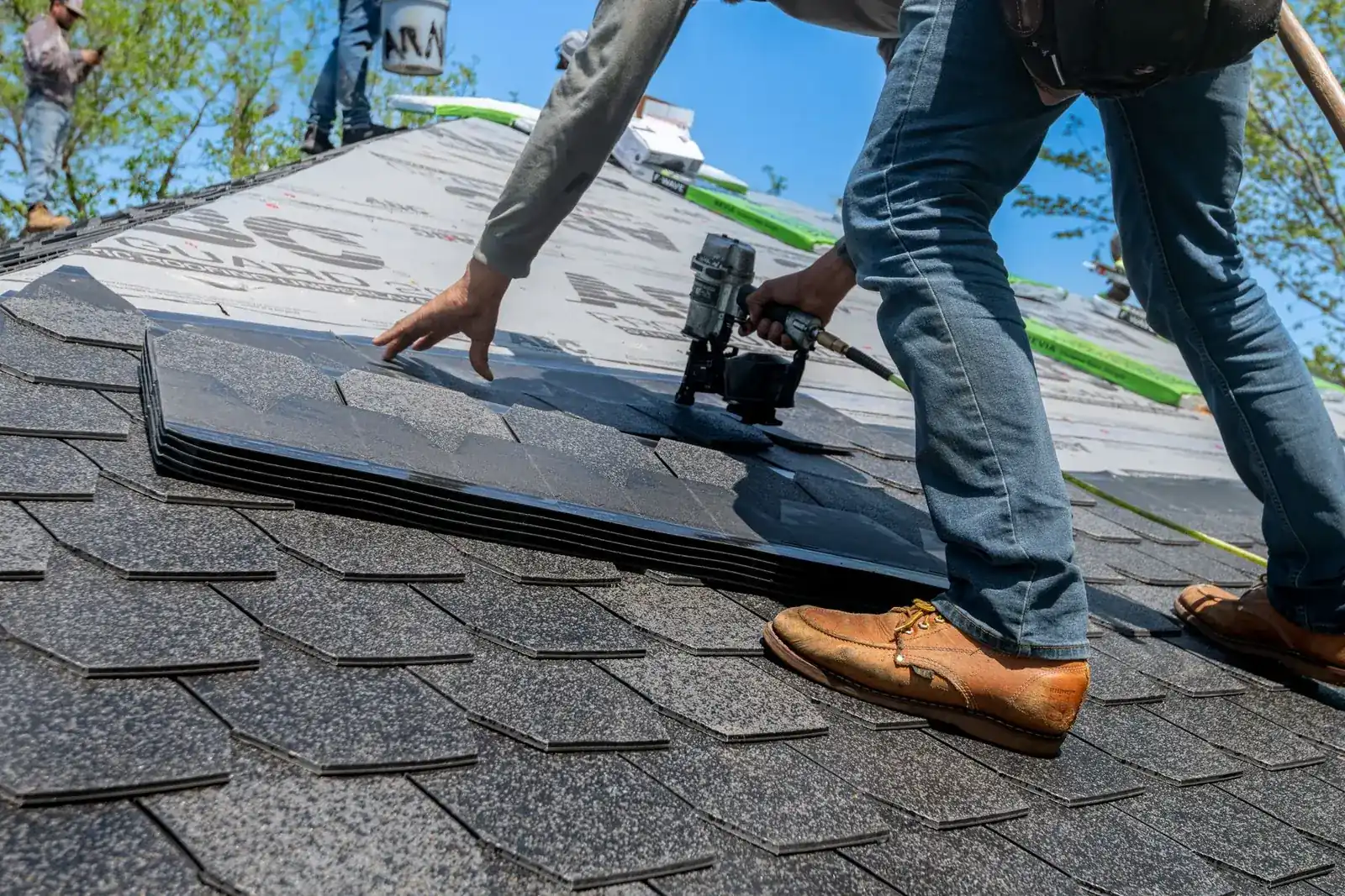 A roofer nailing new shingles onto a roof